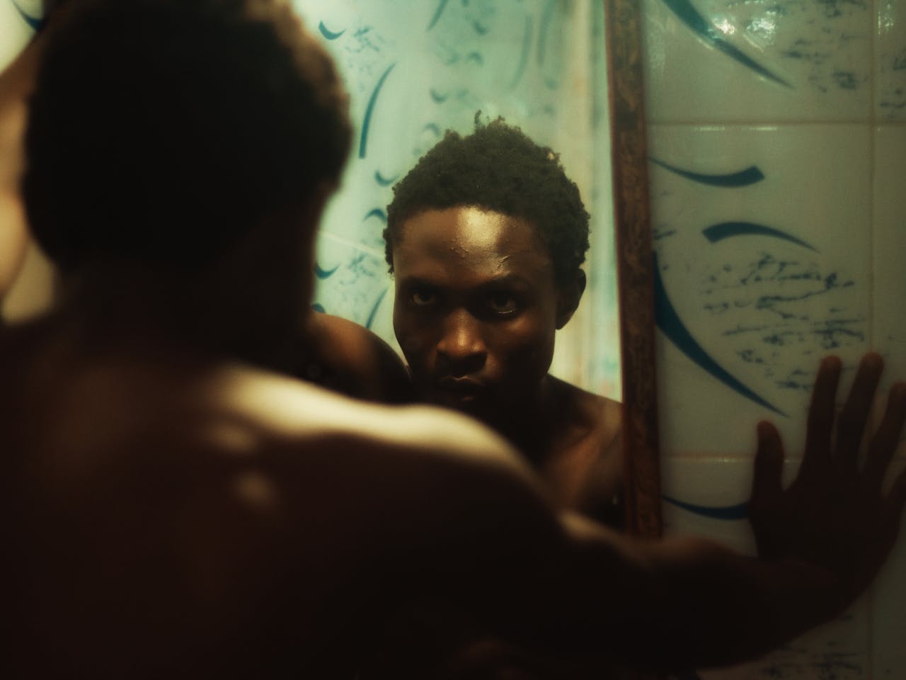 A reflective moment captured with a thoughtful atmosphere as a man gazes intensely into a mirror.