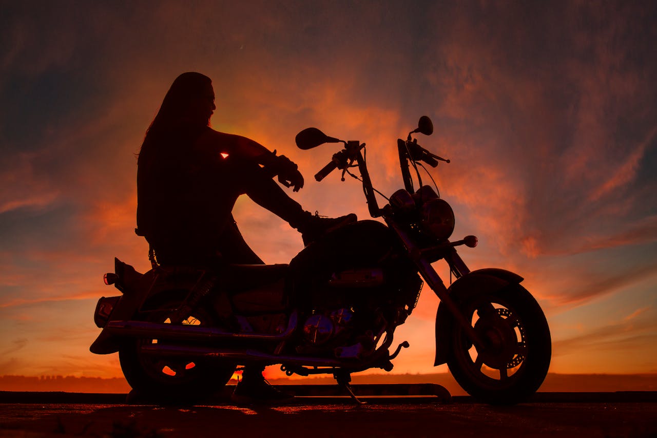 Silhouette of a motorcyclist sitting on a bike against a vibrant sunset in Istanbul, Turkey.